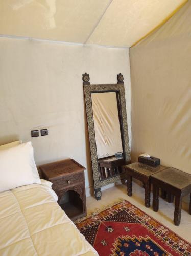 a bedroom with a bed and a mirror and a table at Merzouga Desert Experience Camp-Erg Chebbi Sunset & Camel Ride in Merzouga
