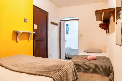 two beds in a room with yellow walls at Posada Hostal Da Rose in Pipa