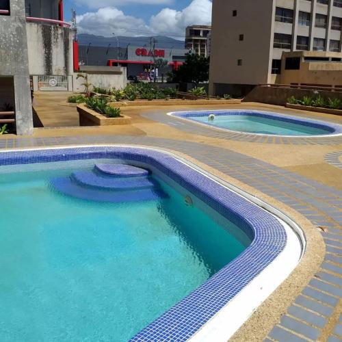 two swimming pools in a building with blue water at PARAJISO en Costa Azul in Porlamar