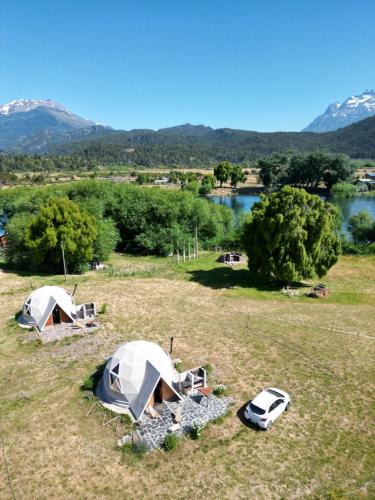 a group of tents in a field next to a river at Nomade Patagonia Glamping & Domos in Trevelin