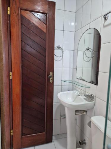 a bathroom with a sink and a wooden door at Hospede-se bem em Salinas in Salinópolis