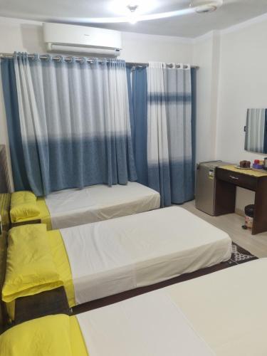 a bedroom with two beds with blue curtains at ABAZIDO Nubian Guest House in Aswan