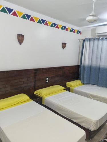 three beds in a room with flags on the wall at ABAZIDO Nubian Guest House in Aswan