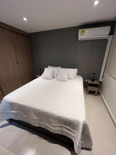 a bedroom with a large bed with white sheets and pillows at Manglar - Ciudad Mallorquin in Puerto Colombia