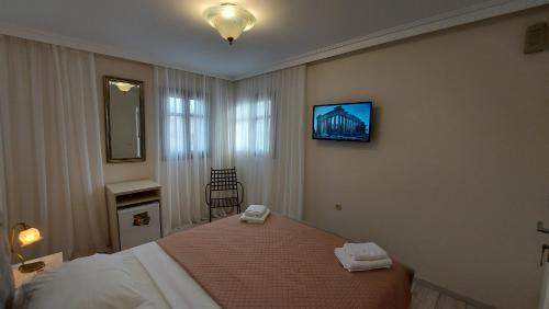a bedroom with a bed and a tv on the wall at Theasis Athens in Athens