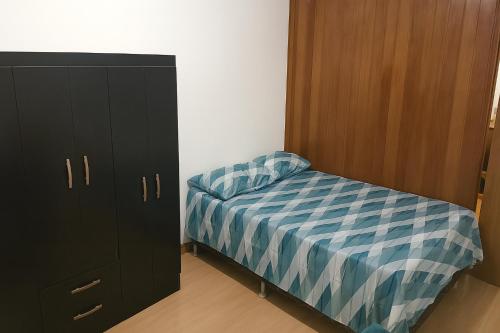 a small bedroom with a bed and a cabinet at Estúdio bem localizado e completo em Teresópolis in Teresópolis