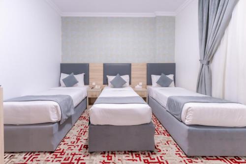 a bedroom with two beds and a rug at Hayah Al Salam Al Fadi Hotel in Medina