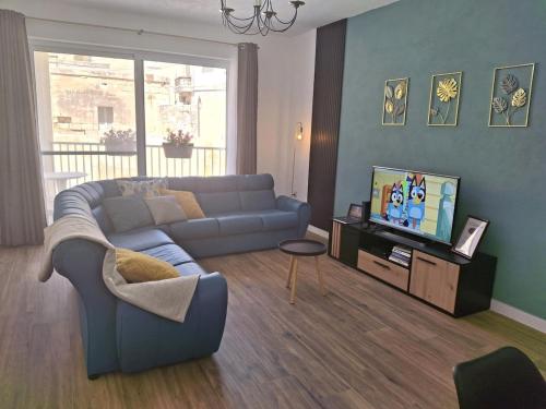 a living room with a blue couch and a tv at Cherry Blossom Apt Courtyard-5min Walk to Centre in Victoria