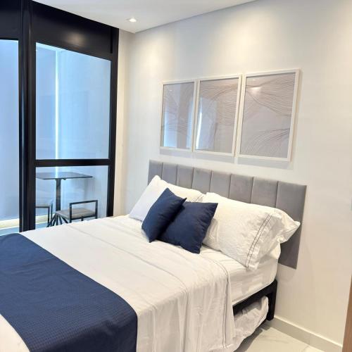 sypialnia z dużym łóżkiem z niebieskimi i białymi poduszkami w obiekcie 103NV Studio Liberdade SP 300 m Estação Liberdade acomoda ate 03 pessoas w São Paulo