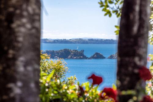 a view of the ocean from behind some trees at An Escape for the Senses in Waiheke Island