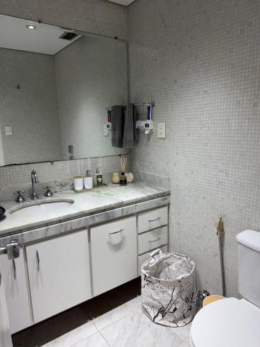 a bathroom with a sink and a mirror at Hospede-se em Alphaville flat moderno com lazer in Barueri