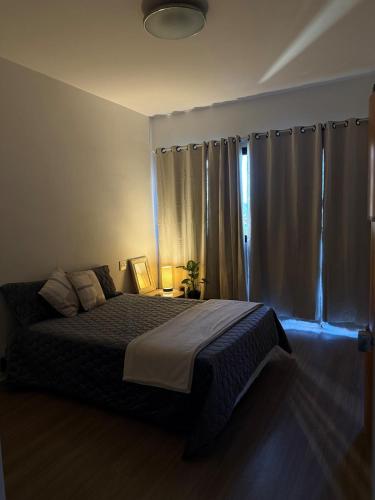 a bedroom with a bed and a window with curtains at Hospede-se em Alphaville flat moderno com lazer in Barueri