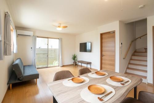 a dining room with a table and chairs and a staircase at Minatogawa Stay OKINAWA in Yaese