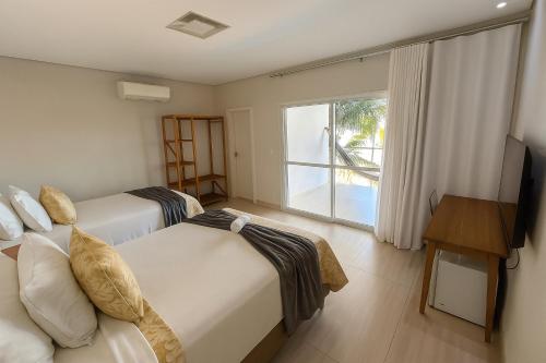 a hotel room with two beds and a television at Pousada Graciosa in Palmas