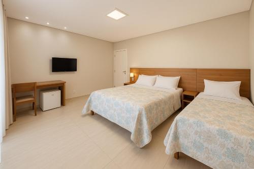 a hotel room with two beds and a television at Pousada Graciosa in Palmas