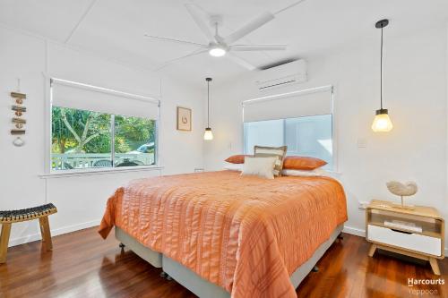 a bedroom with a bed with an orange bedspread and a window at Cooee Bay Beach House in Yeppoon