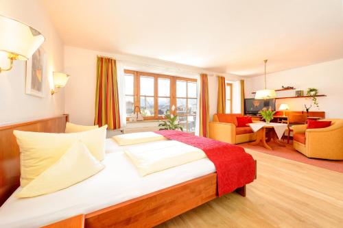 a bedroom with a large bed and a living room at Familien- und Wellnesshotel "Viktoria" in Oberstdorf