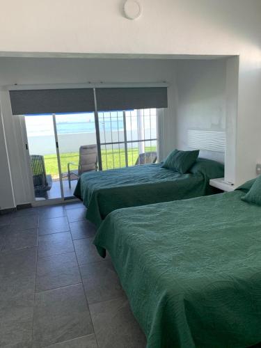 two beds in a room with a view of the ocean at Casa GALLARDO in Manzanillo