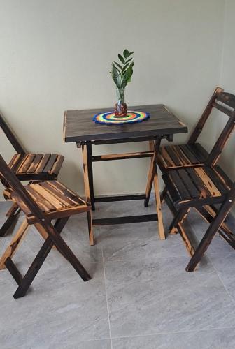 a wooden table with two chairs and a potted plant at Casa vila costeira Guriú in Guriú