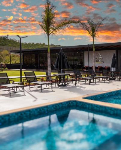 a resort pool with tables and chairs and palm trees at Cipó Chalés in Jaboticatubas
