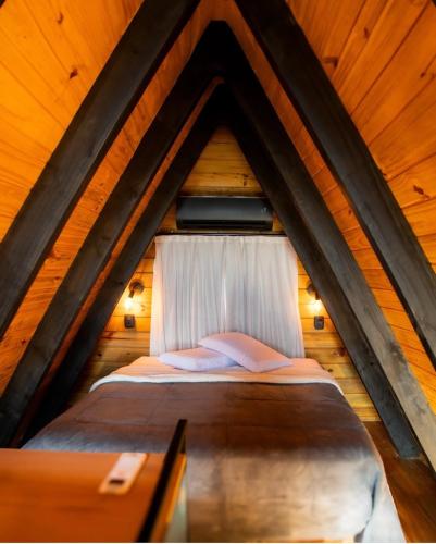a bed in a wooden attic with a window at Pousada Cipó Chalés - Serra do Cipó in Serra do Cipo