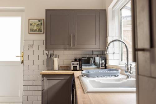 レッドカーにあるThe Skippers Rest Coastal Homeのキッチン(ブラウンキャビネット、シンク付)