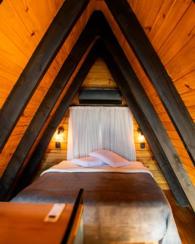 a bed in a wooden attic with a window at Cipó Chalés in Jaboticatubas