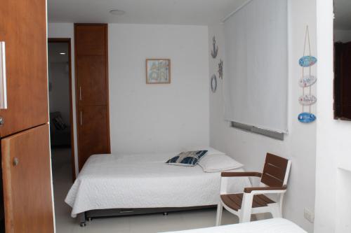 ein kleines Schlafzimmer mit einem Bett und einem Stuhl in der Unterkunft Encantador Apartamento El Laguito Bocagrande in Cartagena de Indias