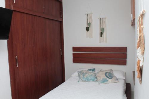 ein Schlafzimmer mit einem Bett und einem Holzschrank in der Unterkunft Encantador Apartamento El Laguito Bocagrande in Cartagena de Indias