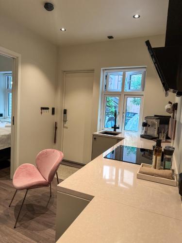 a kitchen with a pink chair next to a counter at Nyrenovert Bergenshus med 2 leiligheter - rolig smau i hjertet av Bergen in Bergen