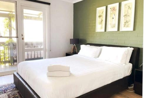 Un dormitorio con una gran cama blanca con una pared verde. en Sea Breeze Villawalk Everywheresunsets, en Fremantle
