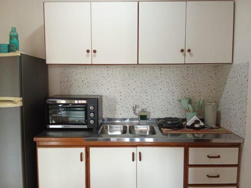 a kitchen with white cabinets and a microwave and a sink at El Depa 5 - Cerca de todo- in Eldorado