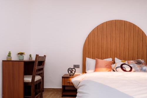 a bed with a wooden headboard and a chair in a bedroom at Nour Mogador in Ghazoua