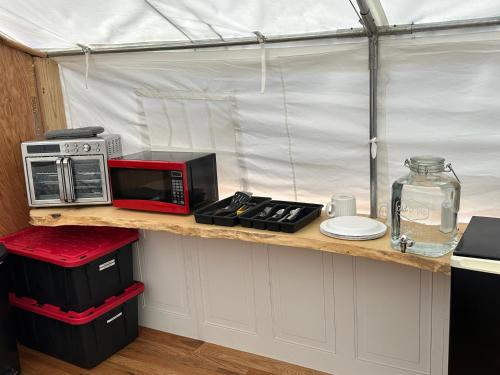 a kitchen with a counter with a microwave and appliances at GlampCamp in Big Arm