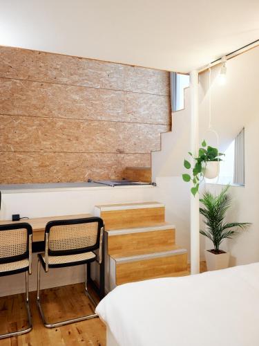 a bedroom with a table and chairs and a staircase at KJ Hotel in Musashino