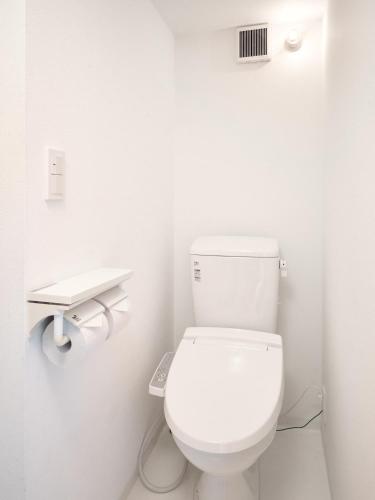 a white bathroom with a toilet and a sink at KJ Hotel in Musashino