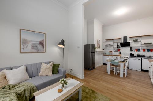 a living room and kitchen with a couch and a table at Cremorne Cottage - MCG, Bars, cafes & Richmond Hub in Melbourne