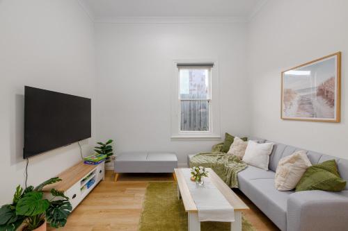 a living room with a couch and a flat screen tv at Cremorne Cottage - MCG, Bars, cafes & Richmond Hub in Melbourne