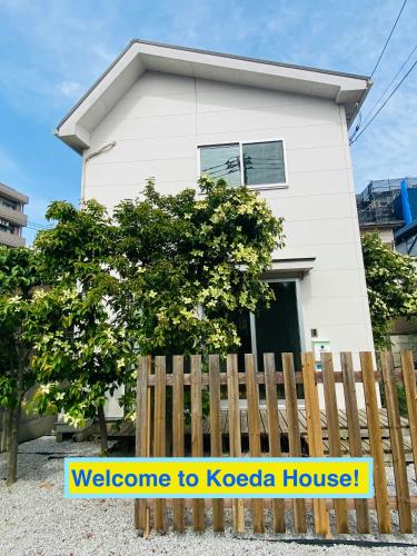 a white house behind a wooden fence at Koeda House in Tokyo