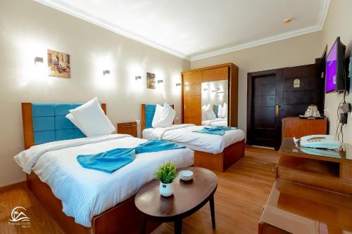 een hotelkamer met twee bedden en een tafel bij Pyramids Oasis Hotel in Caïro
