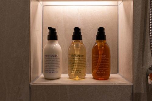 three bottles of soap and shampoo sitting on a shelf at HOTEL R9 Premium Kawamataekimae in Ōra