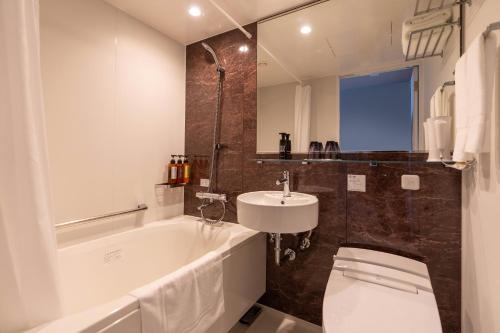 a bathroom with a tub and a sink and a toilet at HOTEL R9 Premium Kawamataekimae in Ōra