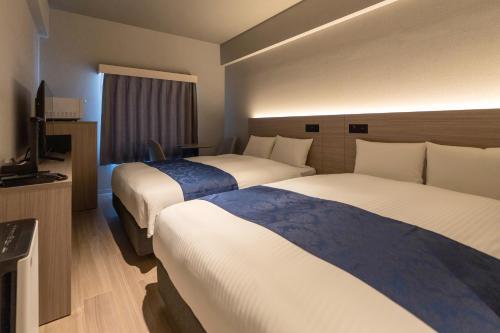 a hotel room with two beds and a television at HOTEL R9 Premium Kawamataekimae in Ōra