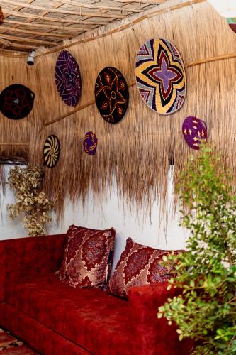a room with a red couch and plates on a wall at Nour Mogador in Ghazoua