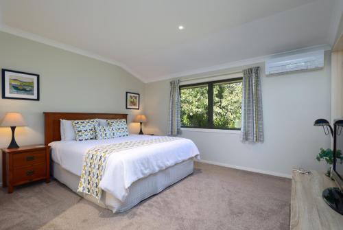 a white bedroom with a bed and a window at Hazelwood Mapua in Mapua