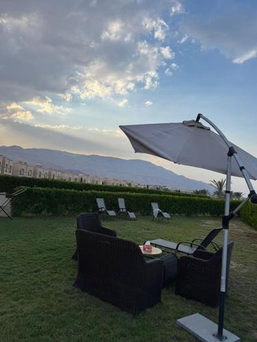 a group of chairs and an umbrella in the grass at 3 bedrooms villa in Ain sokhna in Ain Sokhna