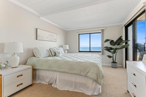 a white bedroom with a bed and a window at Bright Oceanfront 2BR Condo Balcony, King Bed & Parking in Ocean City