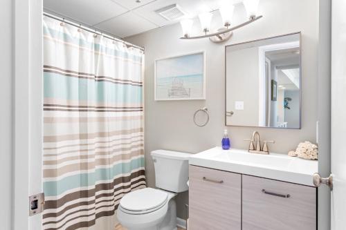 a bathroom with a sink and a toilet and a mirror at Bright Oceanfront 2BR Condo Balcony, King Bed & Parking in Ocean City