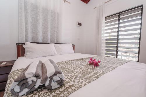 a white bed with towels and pink flowers on it at Lake Side Villa Naisoso in Nadi