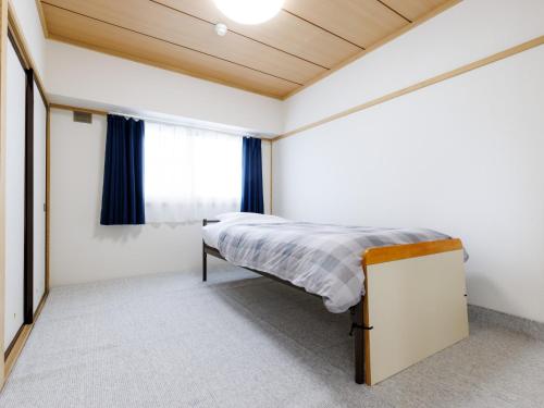 a bedroom with a bed and a window at Tabist JKNツインホテル in Asahikawa